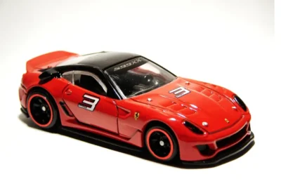 Imagem de um carro de corrida em escala 1:18, estilo Ferrari vermelha com detalhes pretos, número 3 na lateral e rodas detalhadas, ideal para colecionadores