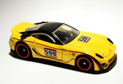 Carro de corrida amarelo com detalhes pretos e rodas vermelhas, de brinquedo ou modelo de alta velocidade, com o número 599 na porta.