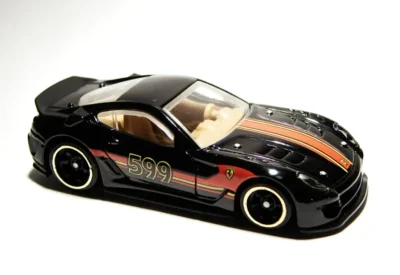 Modelo de carro de corrida preto com detalhes vermelhos e número 599, aparência esportiva e moderna, em fundo branco.